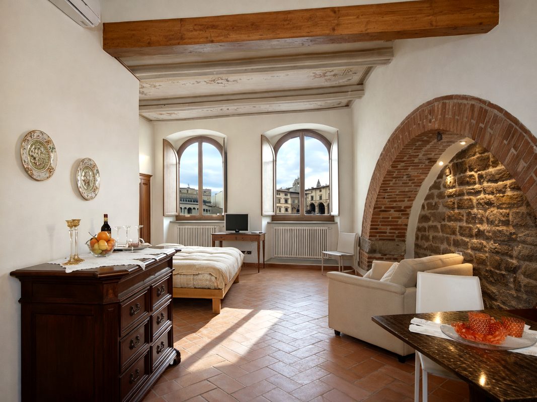 camera-michelangelo-affittacamere-arezzo Camera Michelangelo ad Arezzo con letto matrimoniale, zona relax e dettagli architettonici storici