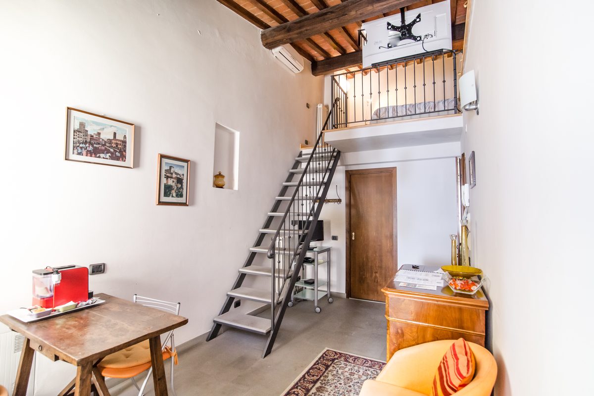 bed-and-breakfast-arezzo-soggiorno-guido-monaco Zona giorno della camera Guido Monaco con tavolo, poltrona e scala per il soppalco
