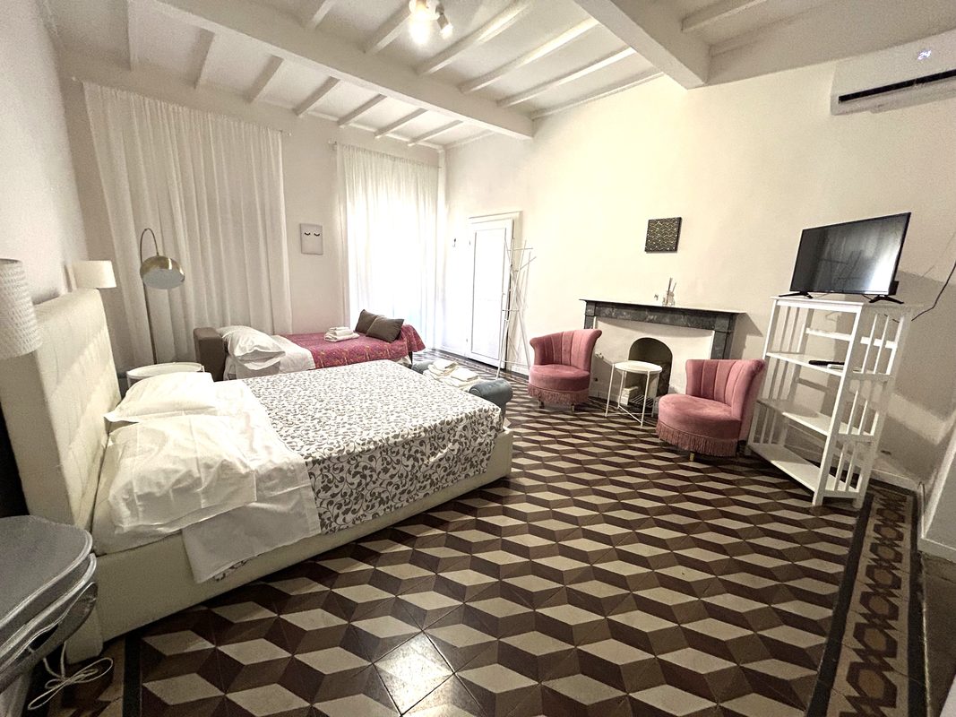 loft-arezzo-camera-tripla-con-camino Ampia camera del Loft 2 ad Arezzo con due letti, camino e poltrone rosa