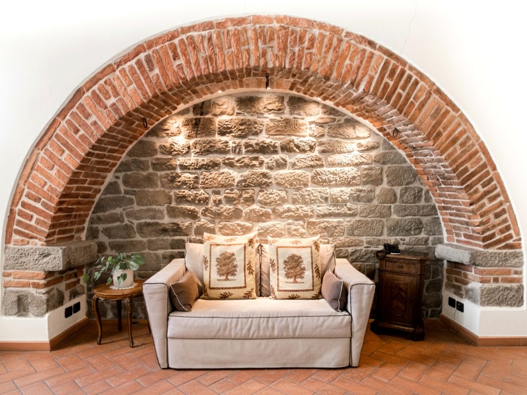 angolo-relax-camera-michelangelo-arezzo Divano nell’antica nicchia in pietra e mattoni della camera Michelangelo
