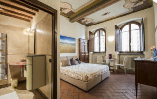 alt="Suite Deluxe Corte del Re centro storico Arezzo, camera spacious con letto king size, bagno in marmo e affreschi originali del palazzo medievale"