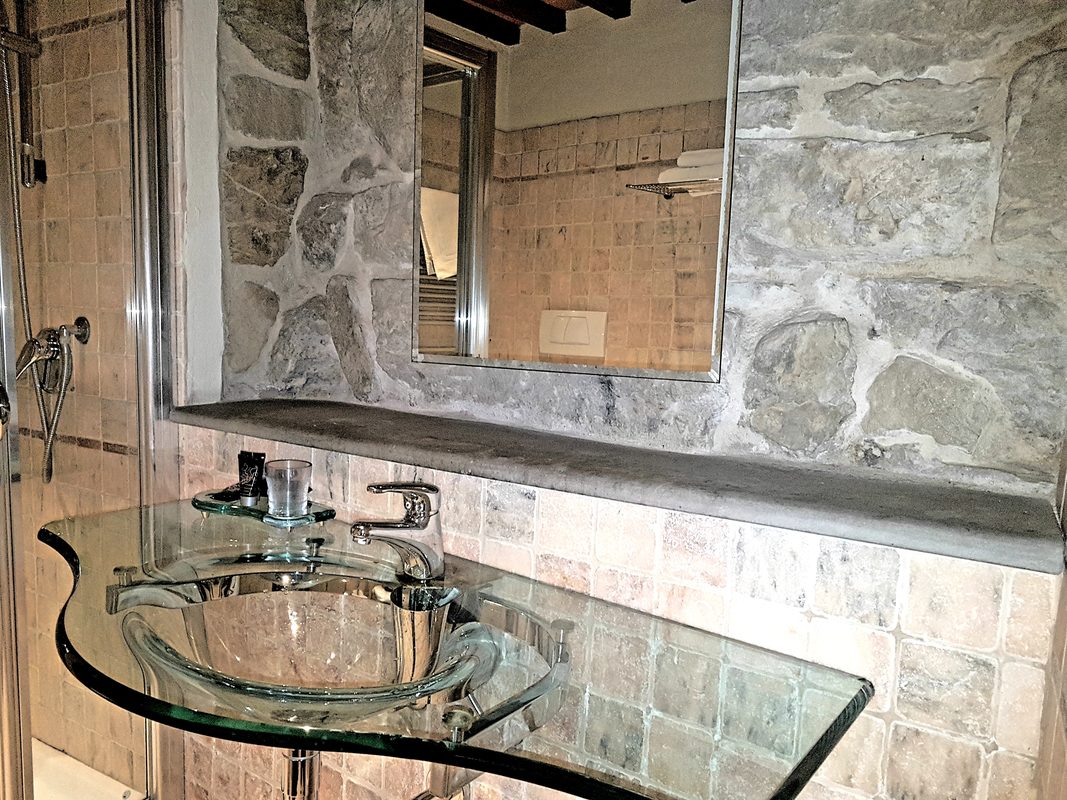 dettaglio-bagno-camera-pietro-aretino Dettaglio del lavabo in vetro e dello specchio nel bagno della camera Pietro Aretino