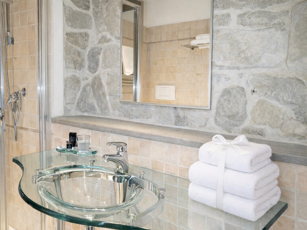 lavabo-in-vetro-bagno-pietro-aretino Lavabo in vetro del bagno con specchio, asciugamani e parete in pietra