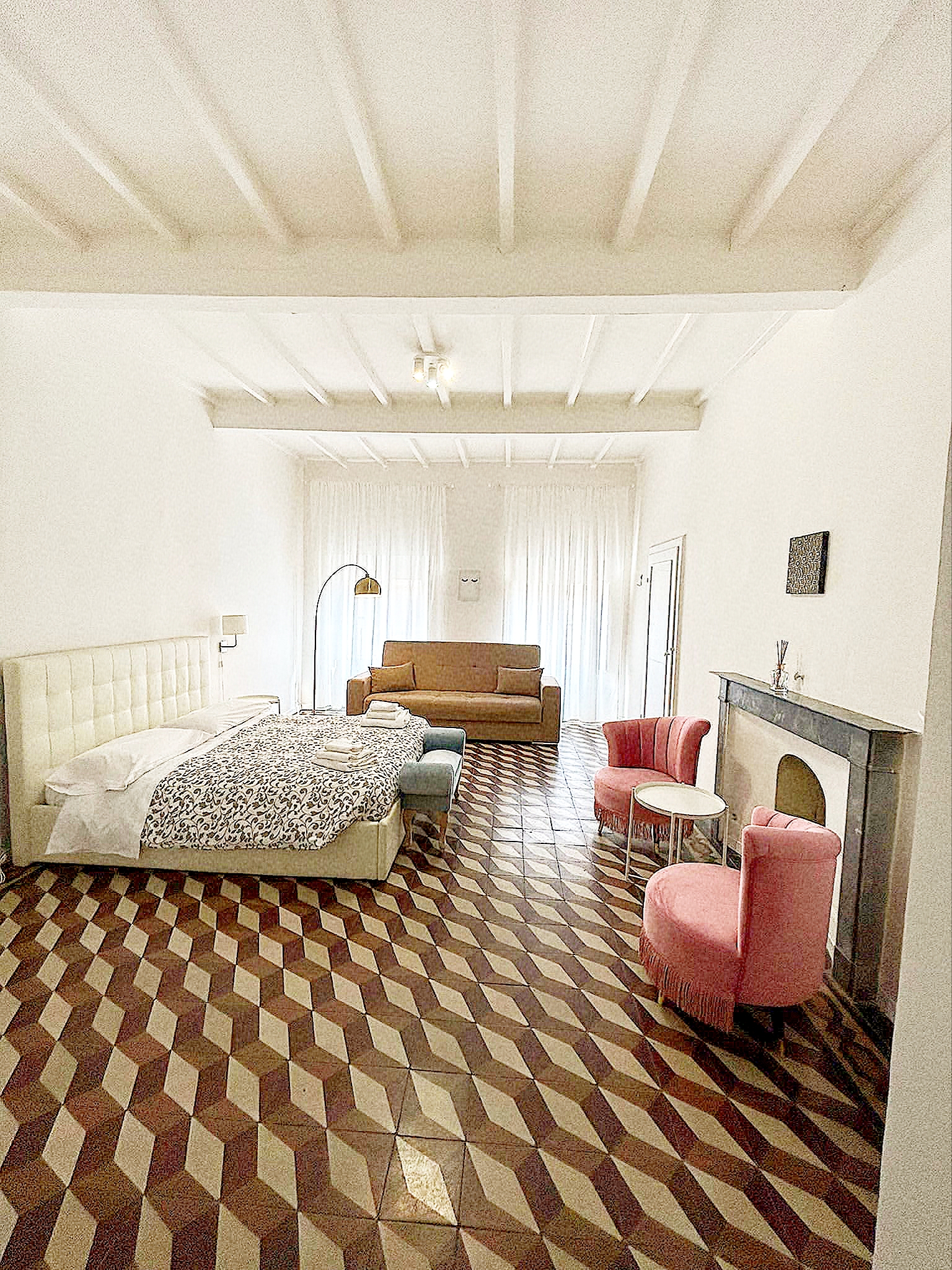 vista-completa-loft-2-108-arezzo Vista panoramica del loft ad Arezzo con zona notte, divano, camino e poltrone rosa