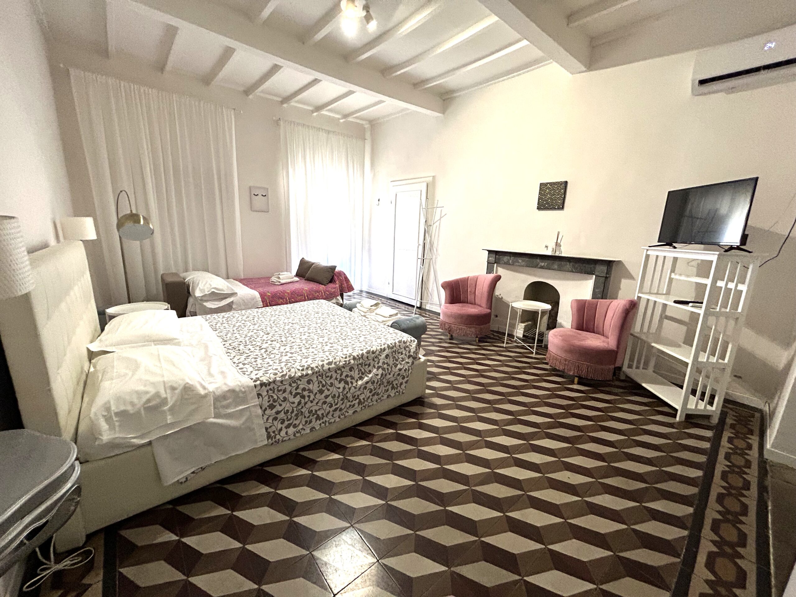 loft-spazioso-per-famiglie-ad-arezzo Vista completa del loft ad Arezzo con letto matrimoniale, letto singolo, poltrone e TV