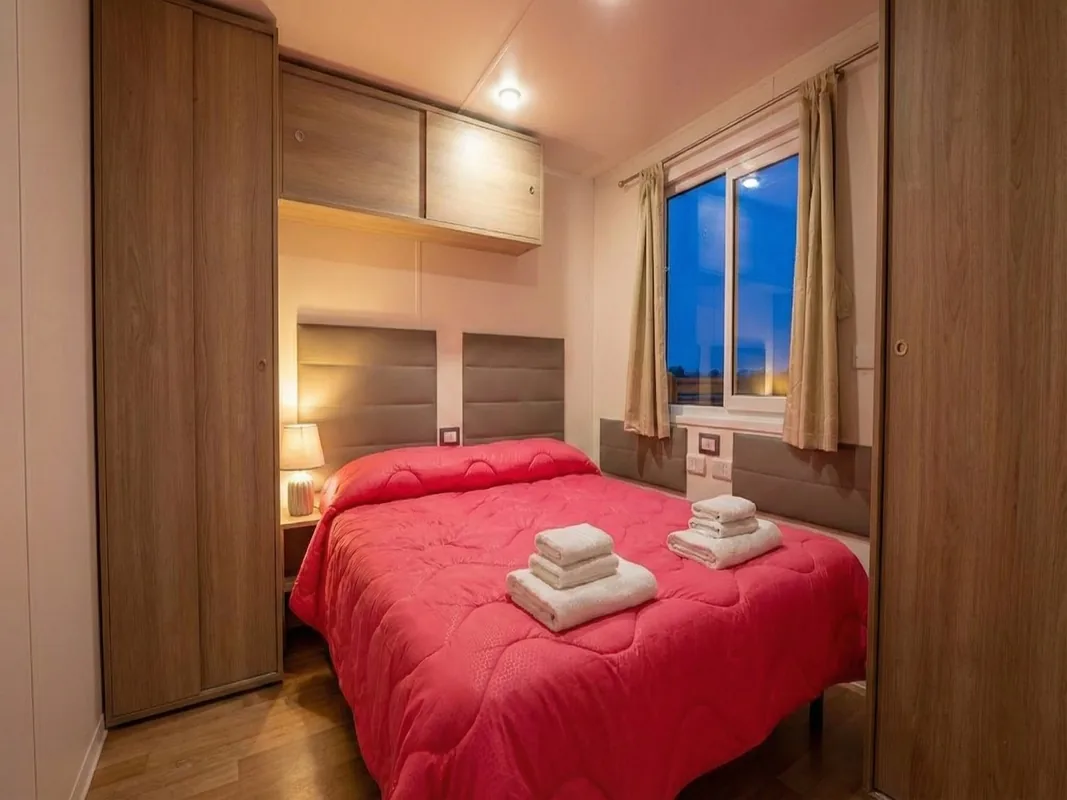 camera-matrimoniale-bungalow-menta-arezzo Camera matrimoniale del bungalow Menta con copriletto rosso e biancheria da bagno