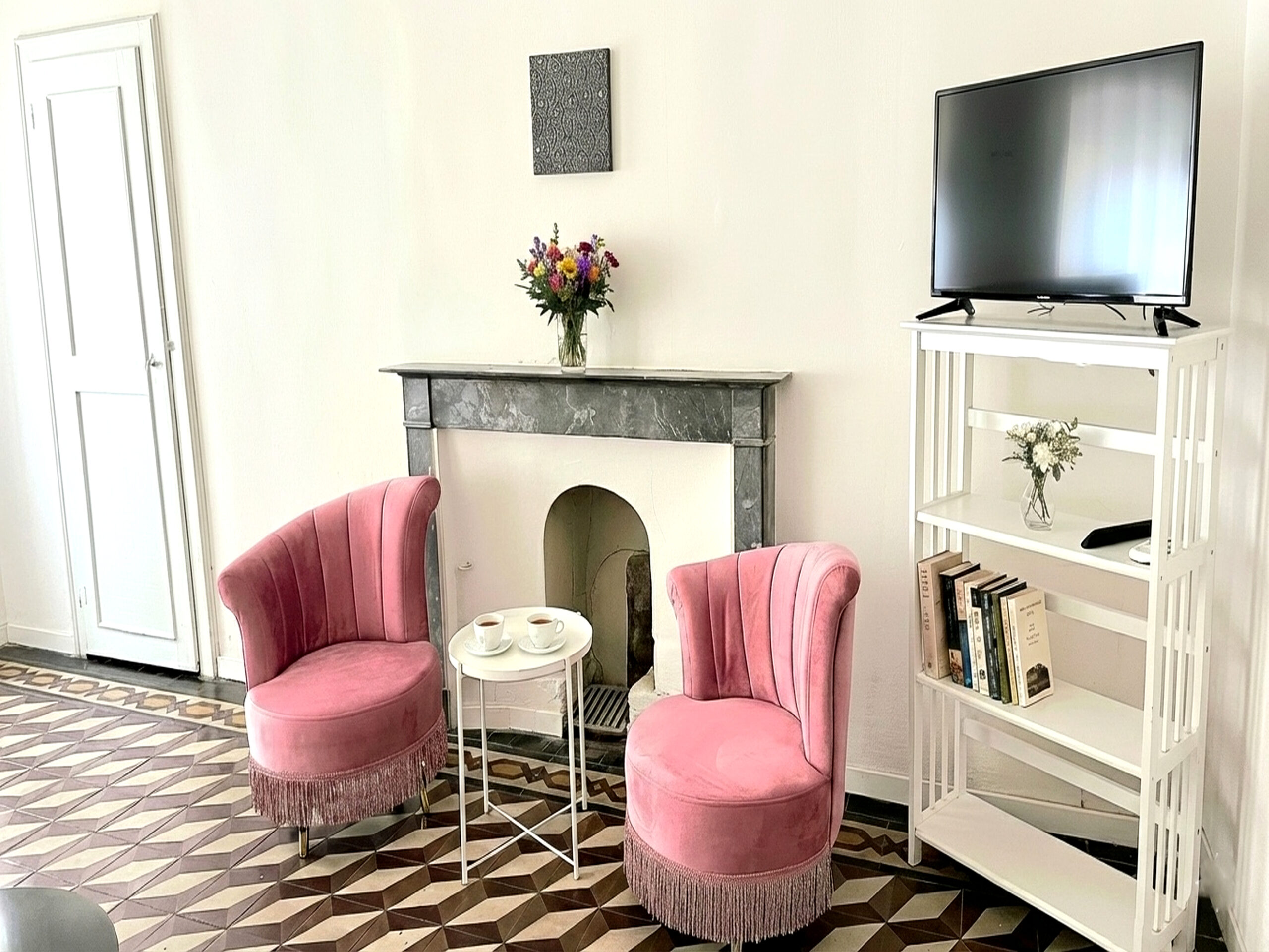 zona-tv-loft-per-soggiorni-brevi-arezzo Zona TV del loft con due poltrone rosa, camino e libreria