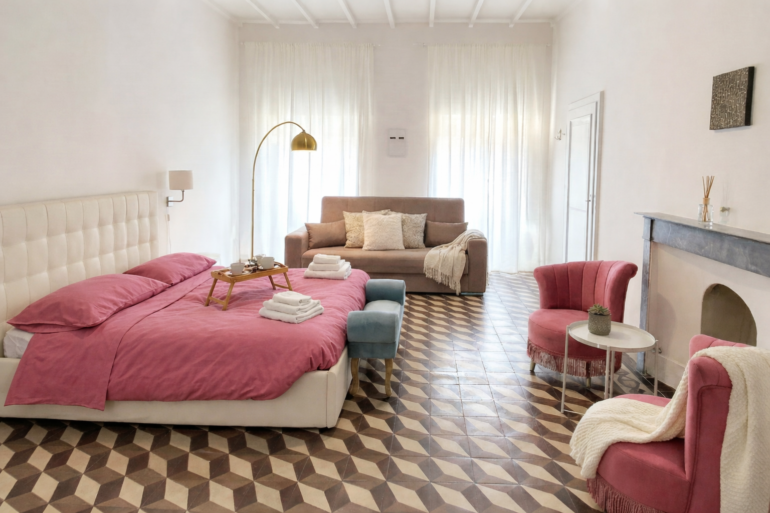 loft-2-108-soggiornare-ad-arezzo Loft ad Arezzo con letto matrimoniale, divano, poltrone rosa e pavimento geometrico