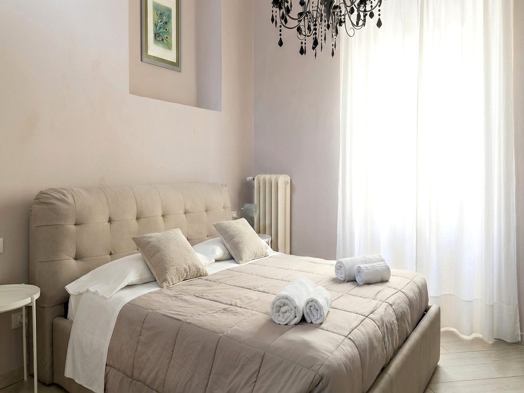 dormire-ad-arezzo-camera-matrimoniale-114 Letto matrimoniale della camera 114 ad Arezzo con biancheria chiara e lampadario nero
