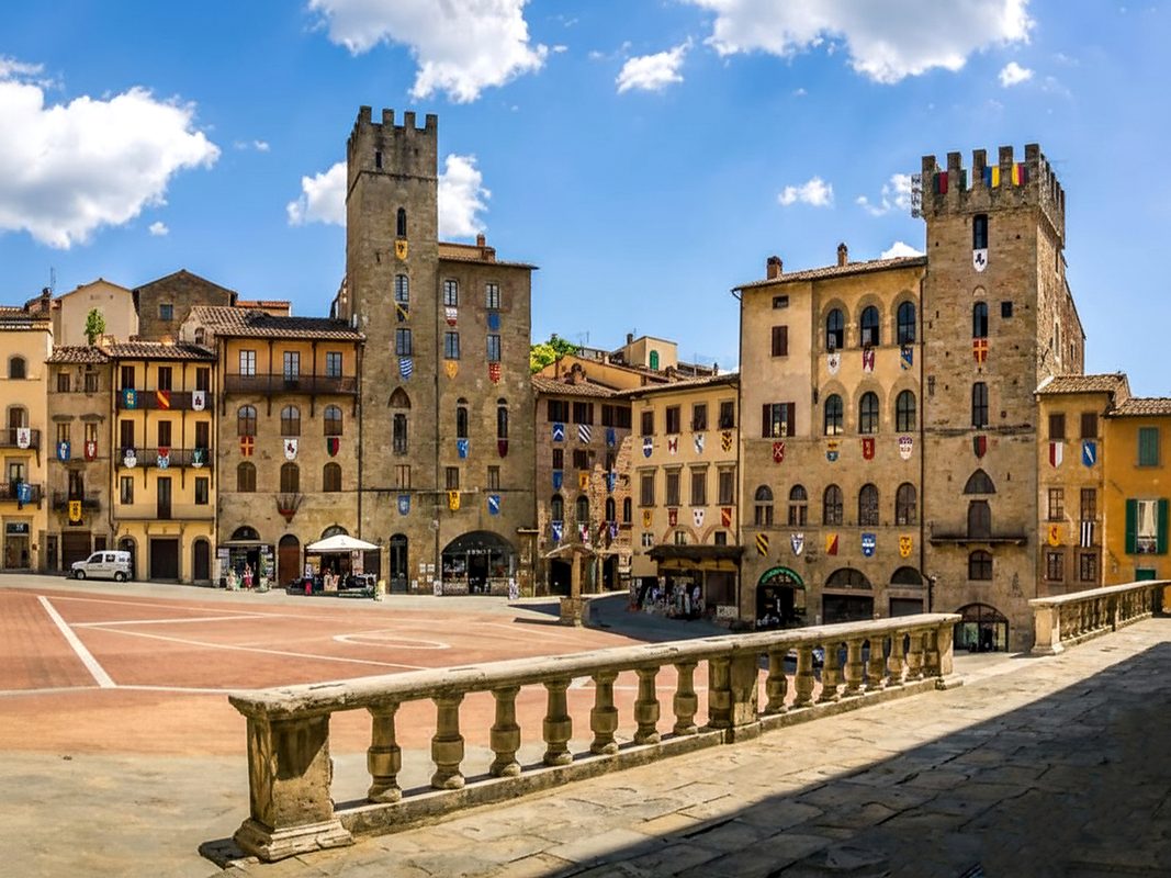 vacanze-in-toscana-piazza-grande-arezzo Piazza Grande ad Arezzo con torri medievali, palazzi storici e stemmi sulle facciate